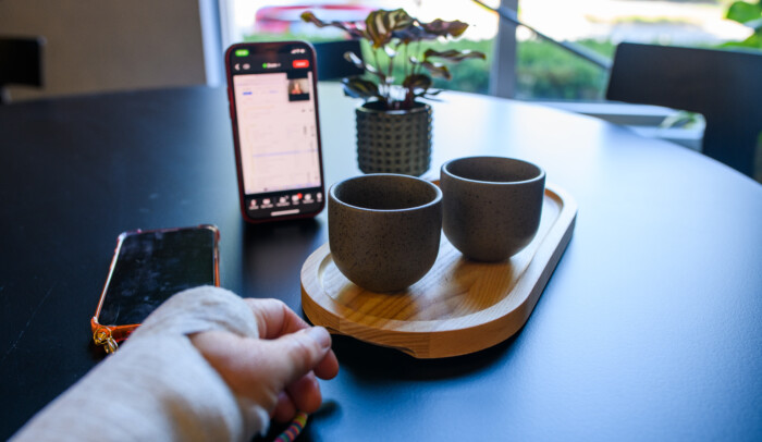 gipsad hand på ett bord med mobiltelefon och koppar